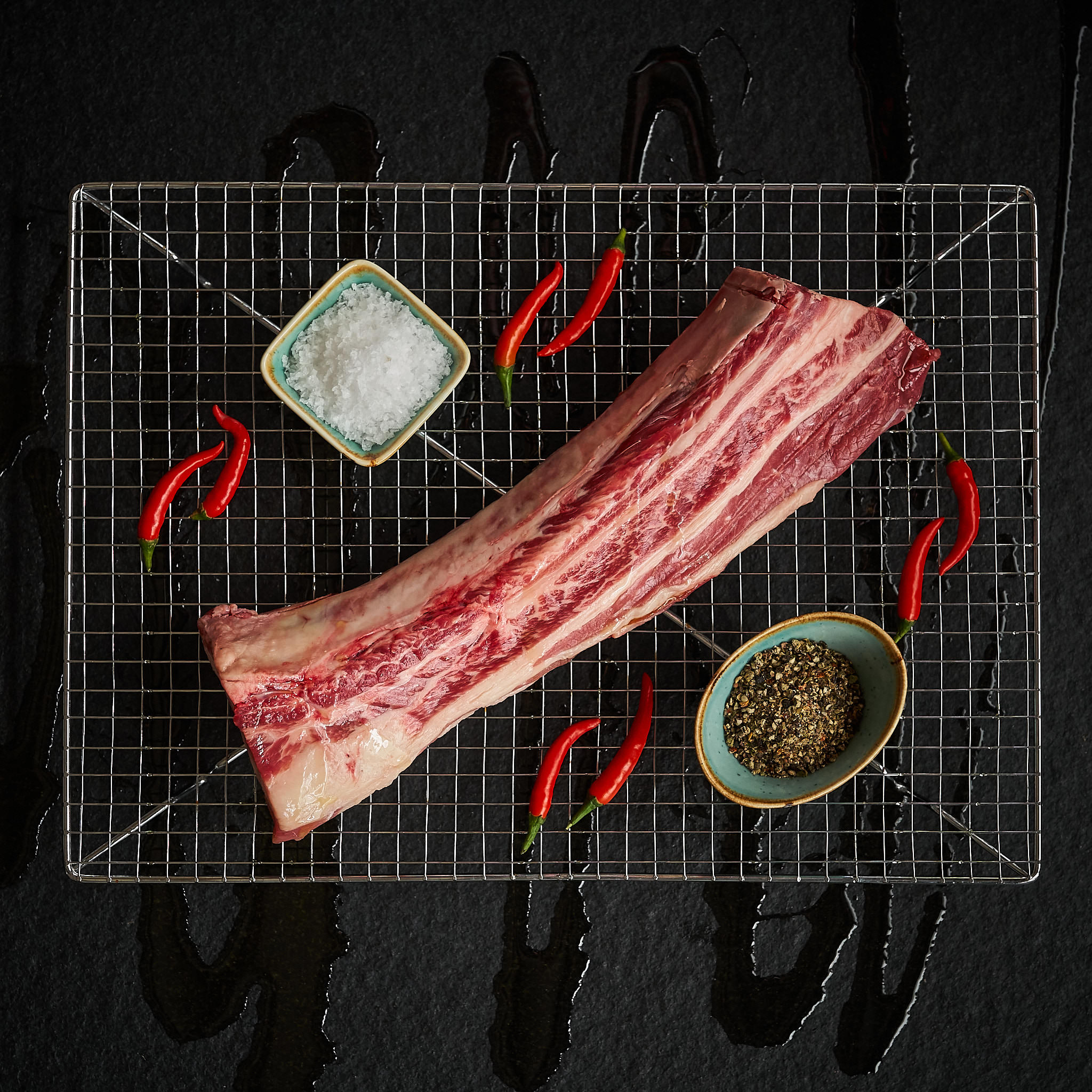 Frische Plateribs mit Salz, Gewuerzen und Chilishoten auf Grillgitter