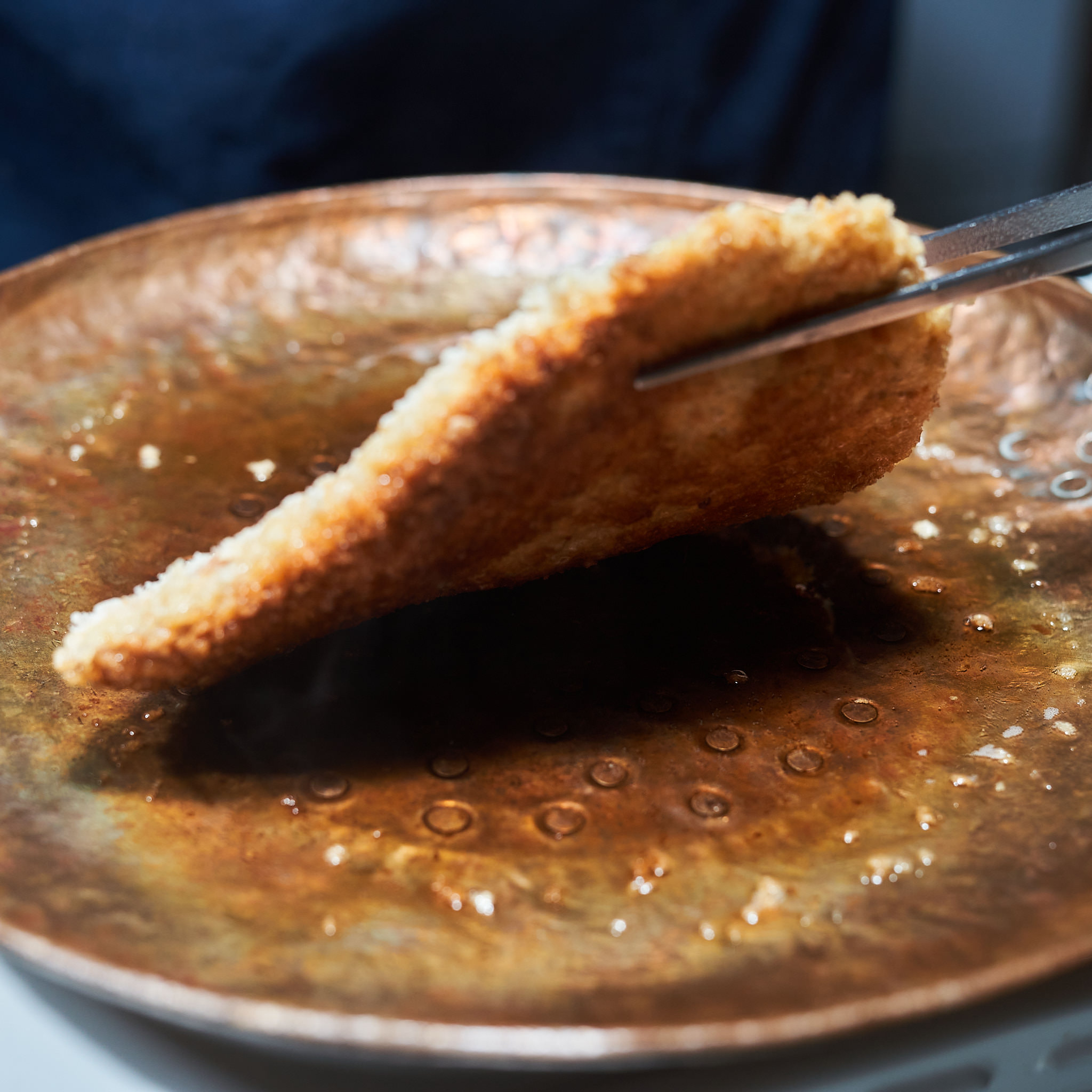 Paniertes Kaiserschnitzel von der Schale wird in der Pfanne gewendet