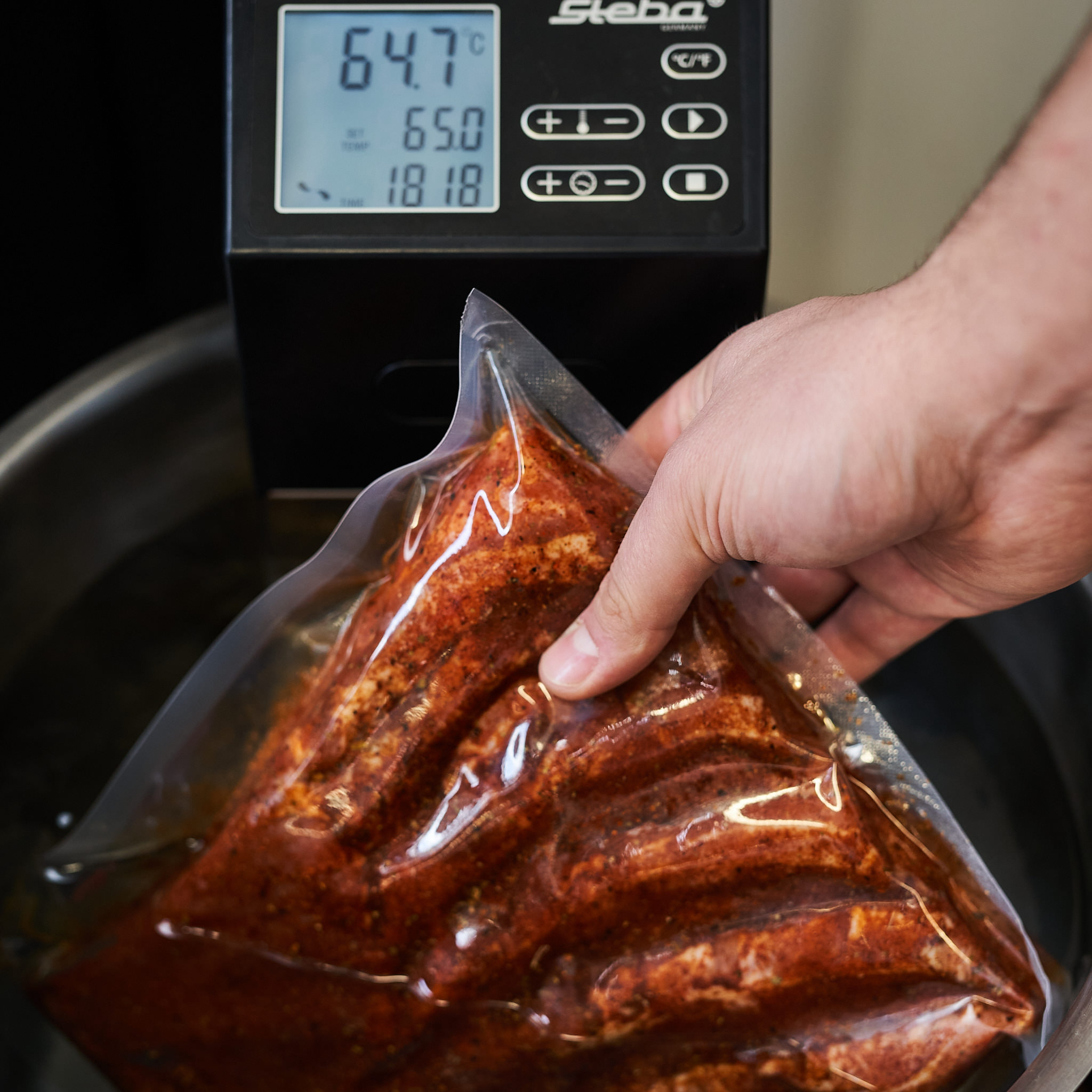 Schweinebauch vom Strohschwein im Vakuumbeutel wird in den Sous-Vide-Garer gelegt