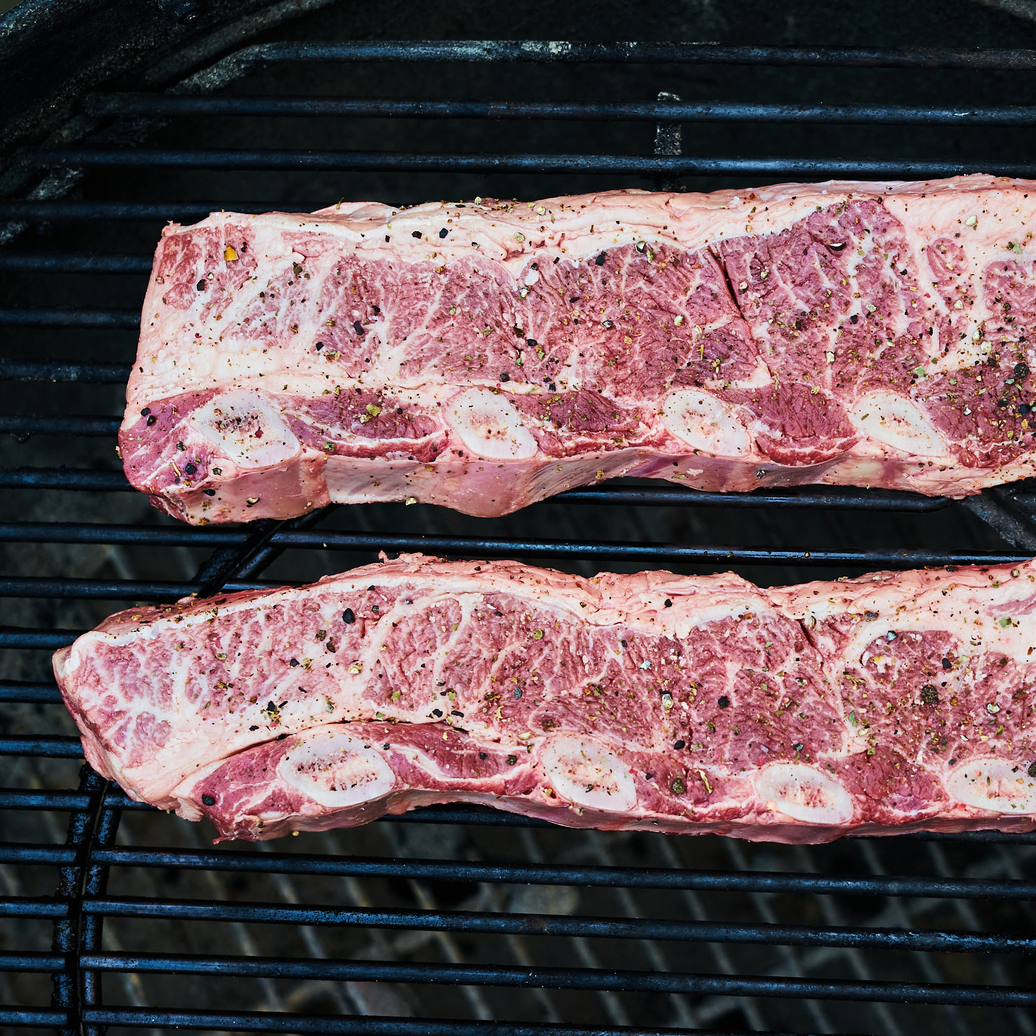 Asado de Tira auf dem Grillgitter gewuerzt mit Pfeffer und Salz