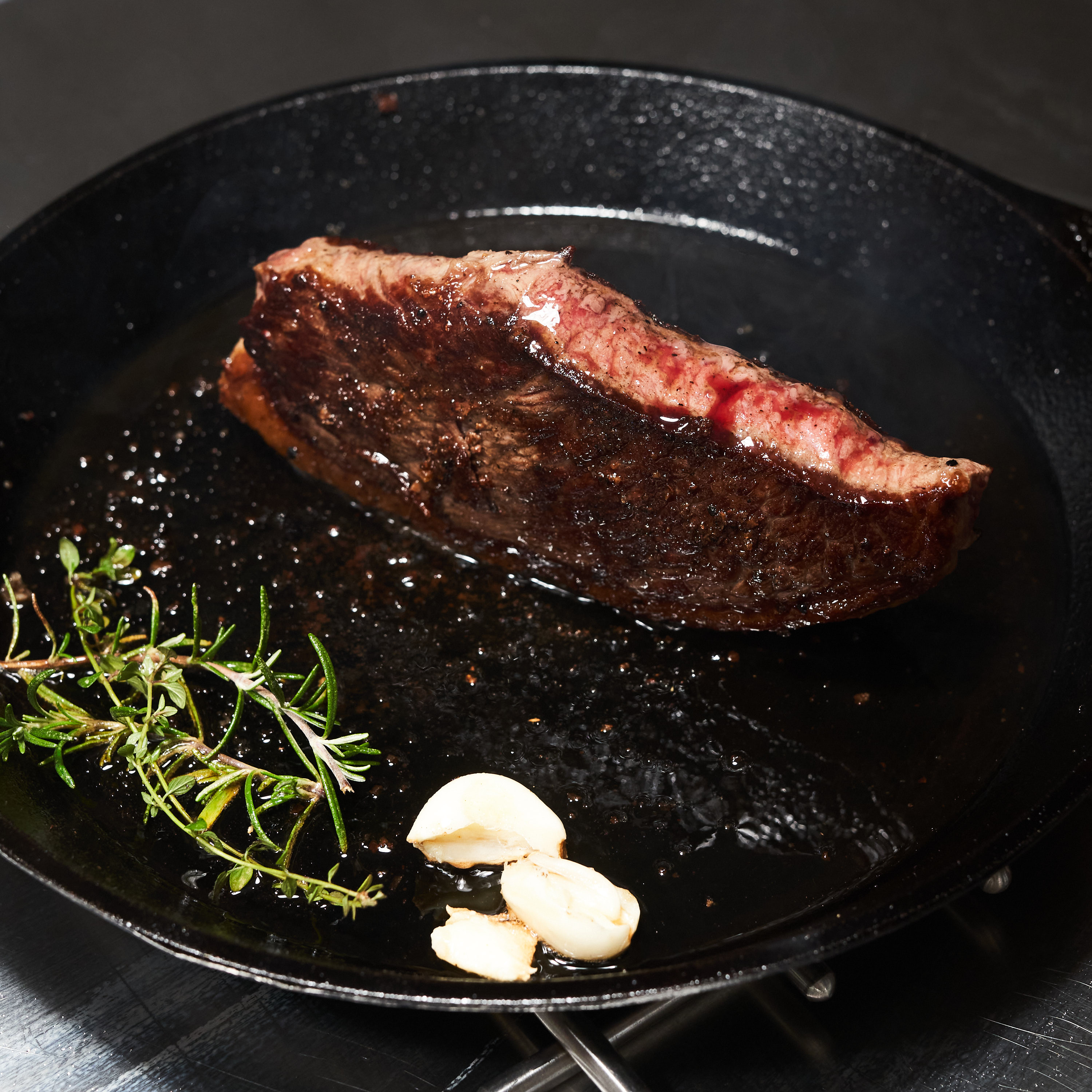 Gegrilltes Picanha Steak in Gusseisenpfanne mit frischem Knoblauch und Rosmarin