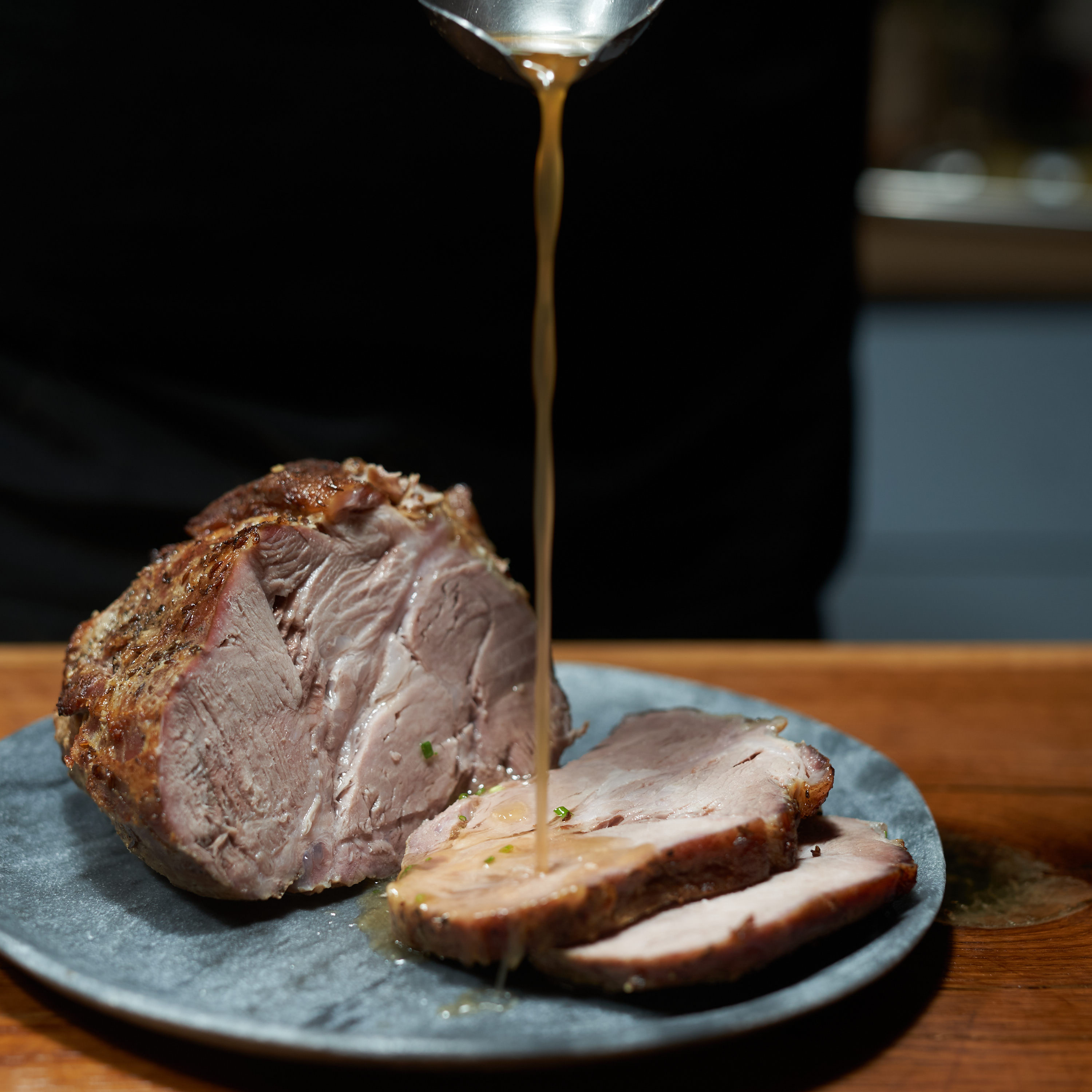 Bratenstück von der Schweineschulter auf Teller serviert und mit Bratensauce übergossen