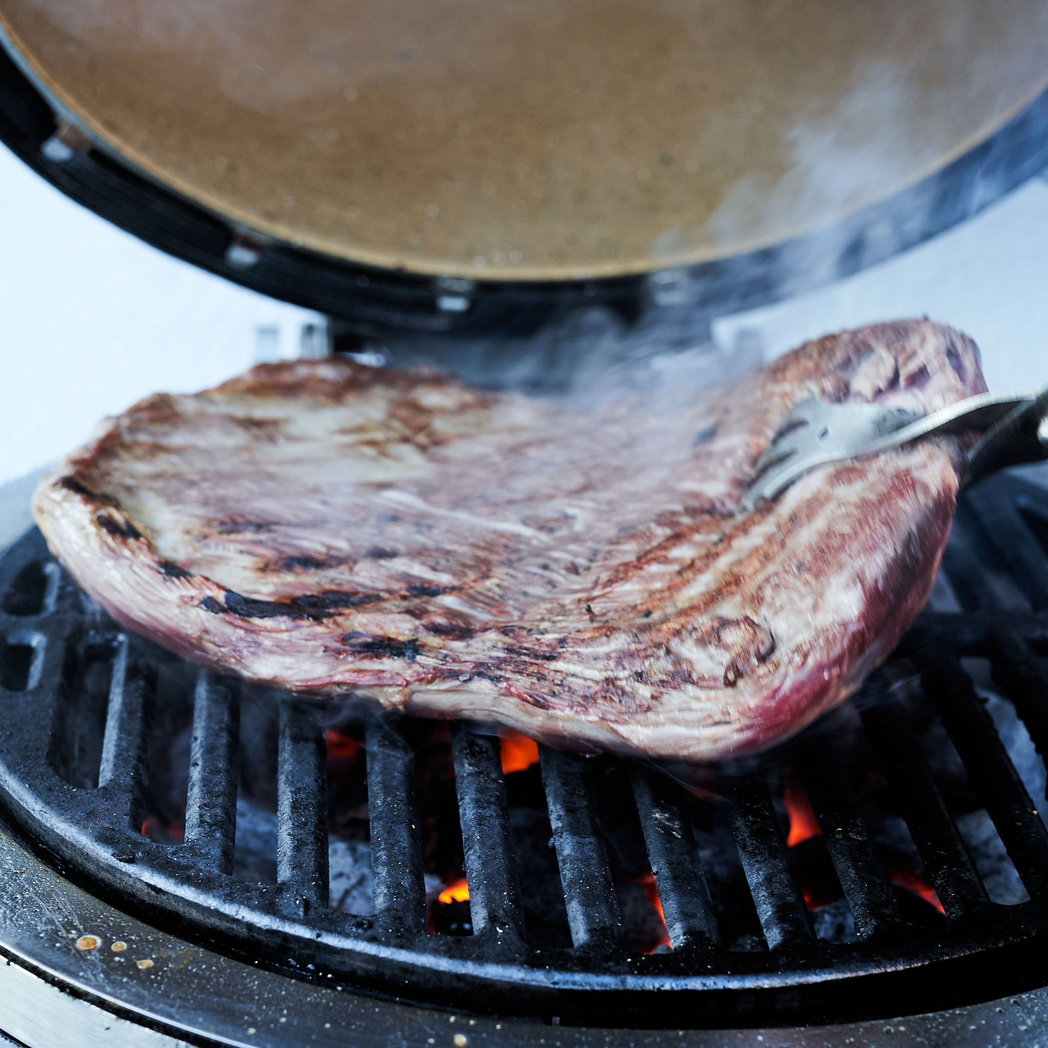 Flanksteak wird auf Grillrost gewendet