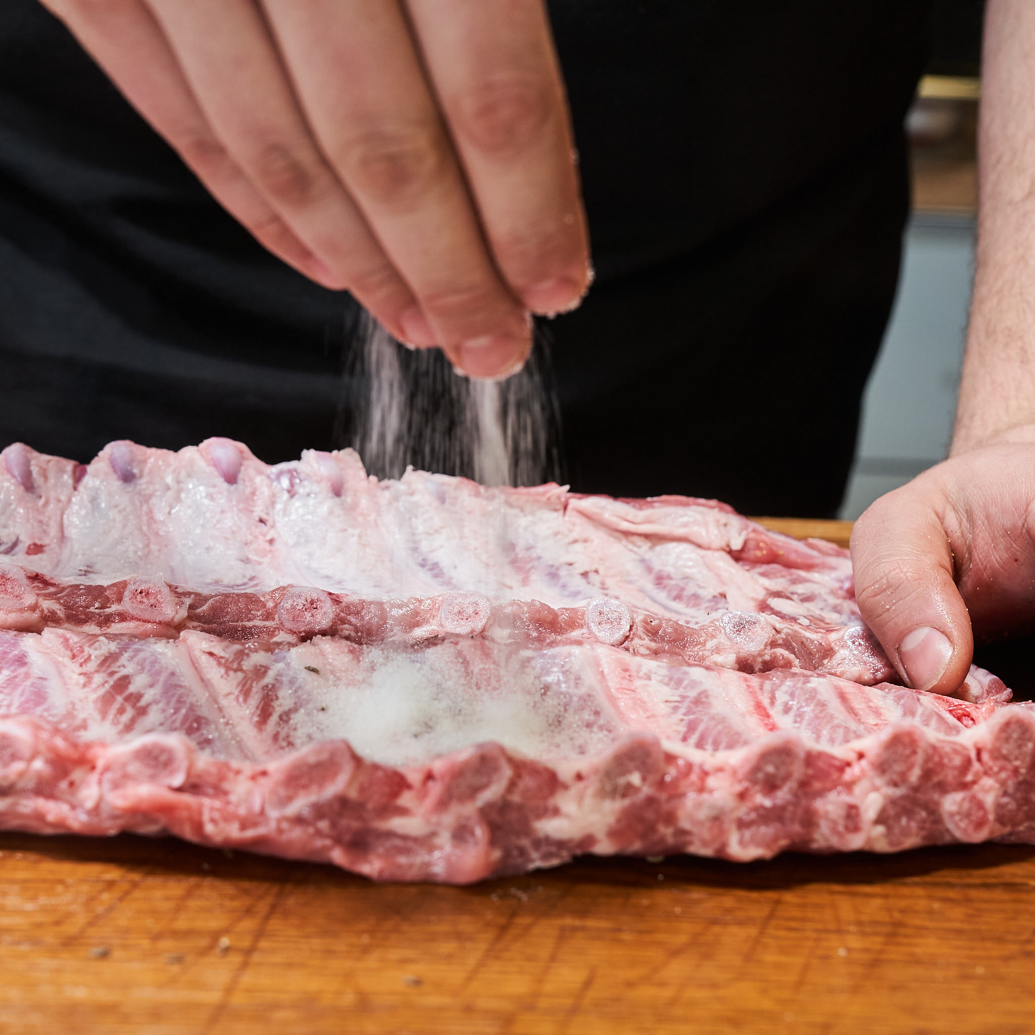 Spareribs vom Strohschwein werden gesalzen