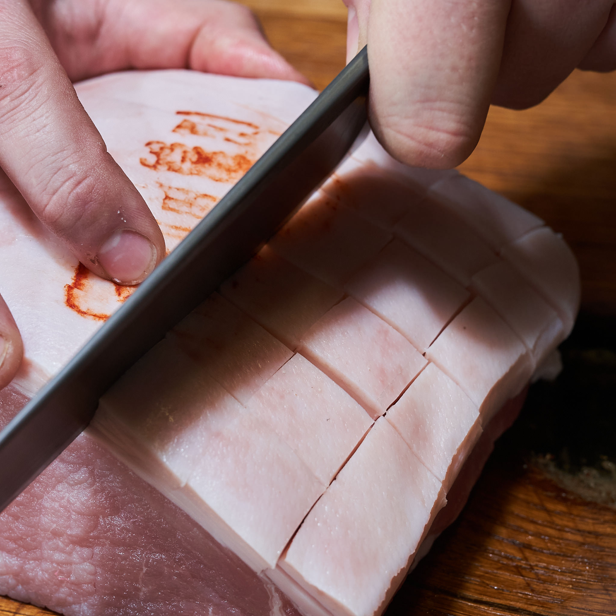 Karree Schwarte wird mit Messer eingeschnitten