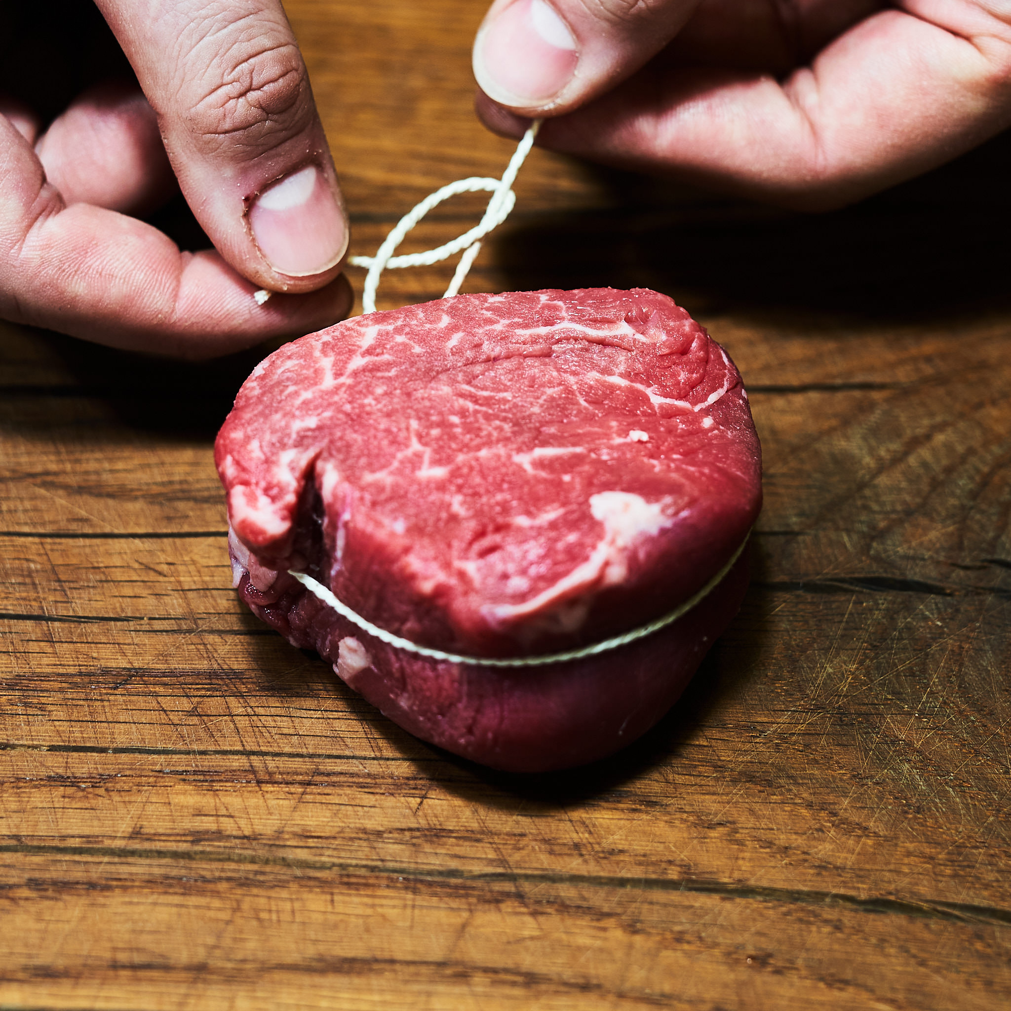 Rinderfilet wird mit duenner Schnur gebunden