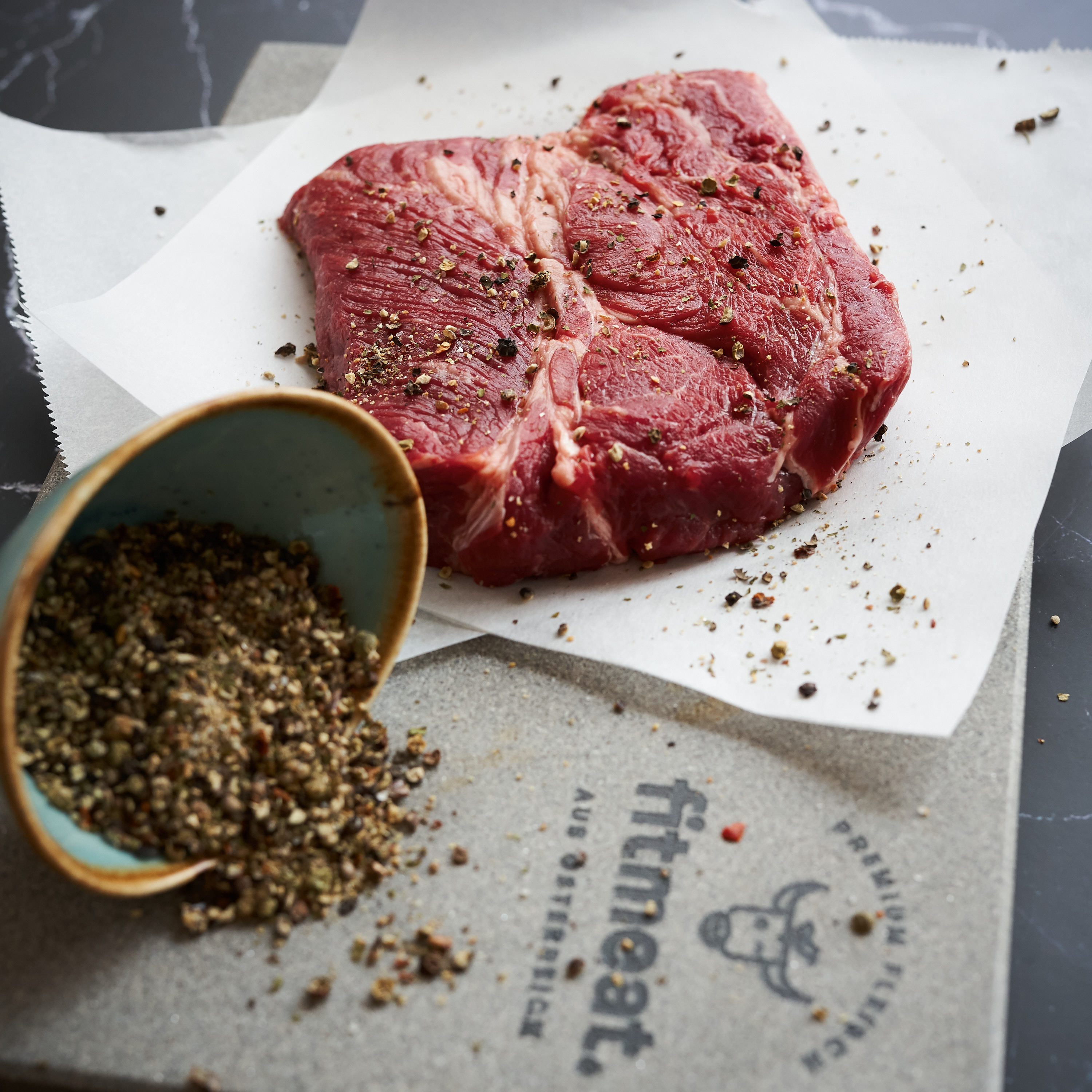 Chucksteak auf Steinplatte mit frischen Gewuerzen