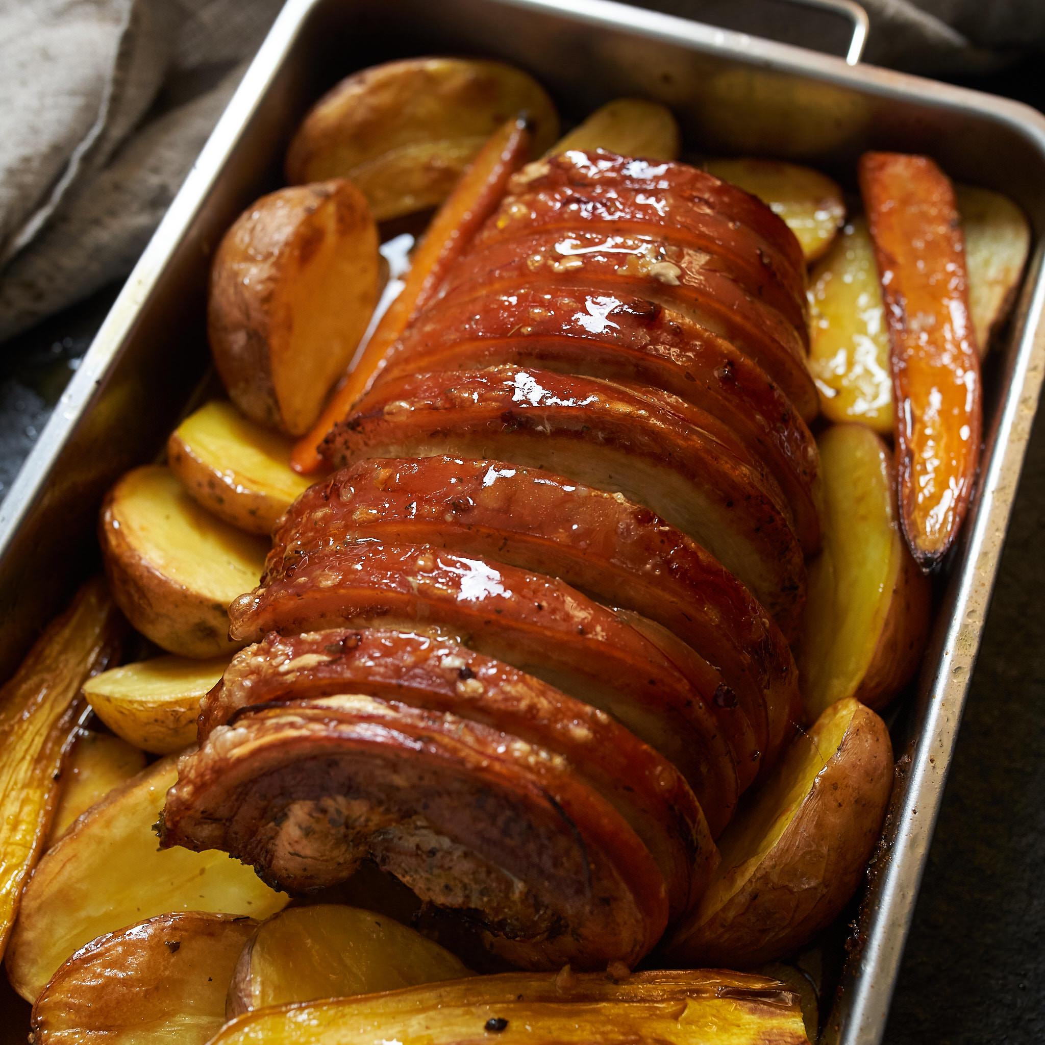 Schopf mit Schwarte gebraten imd auf Ofenkartoffel-Scheiben serviert