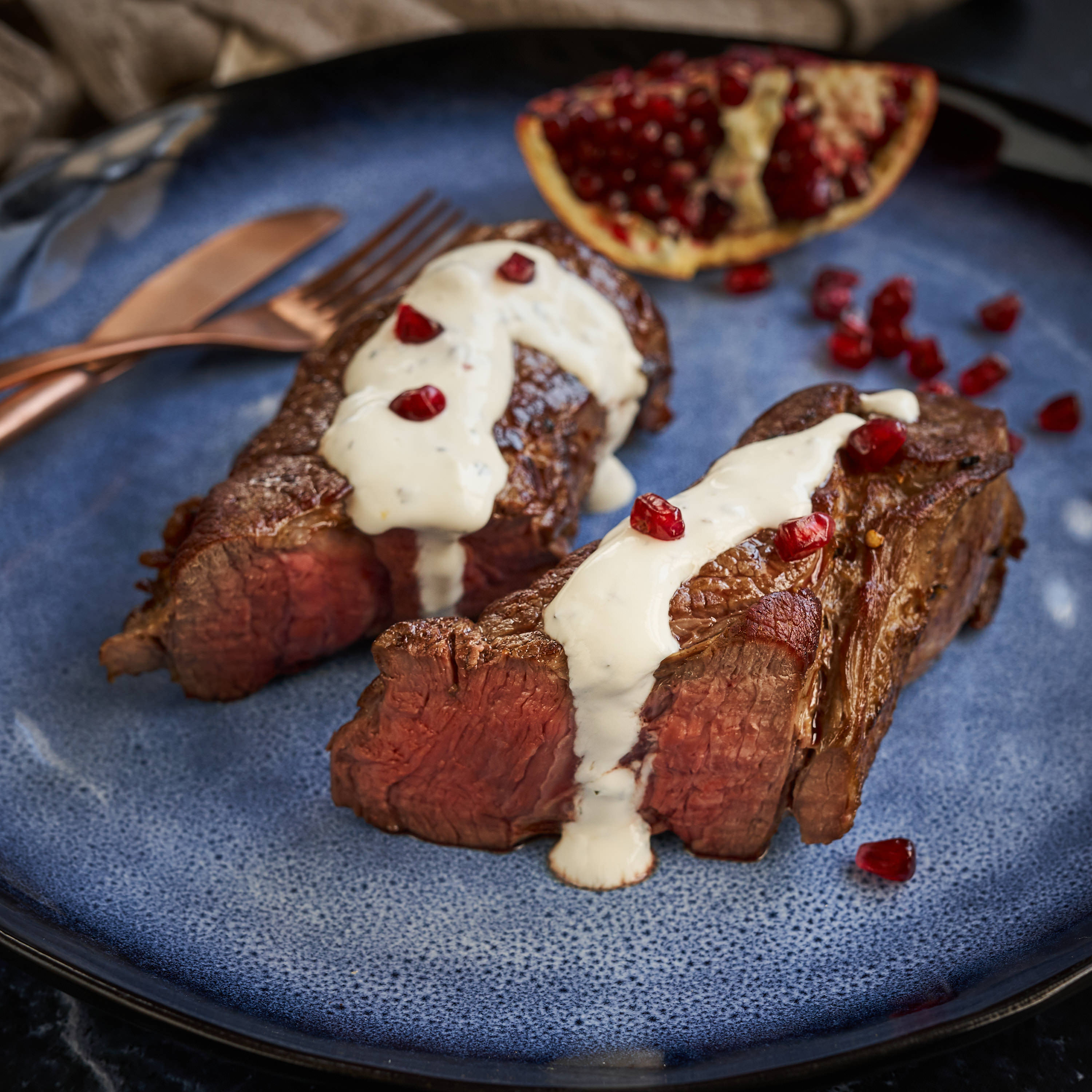 Saftig gegrillte Denver Cut Steaks auf blauem Teller serviert mit selbstgemachter weisser Sauce