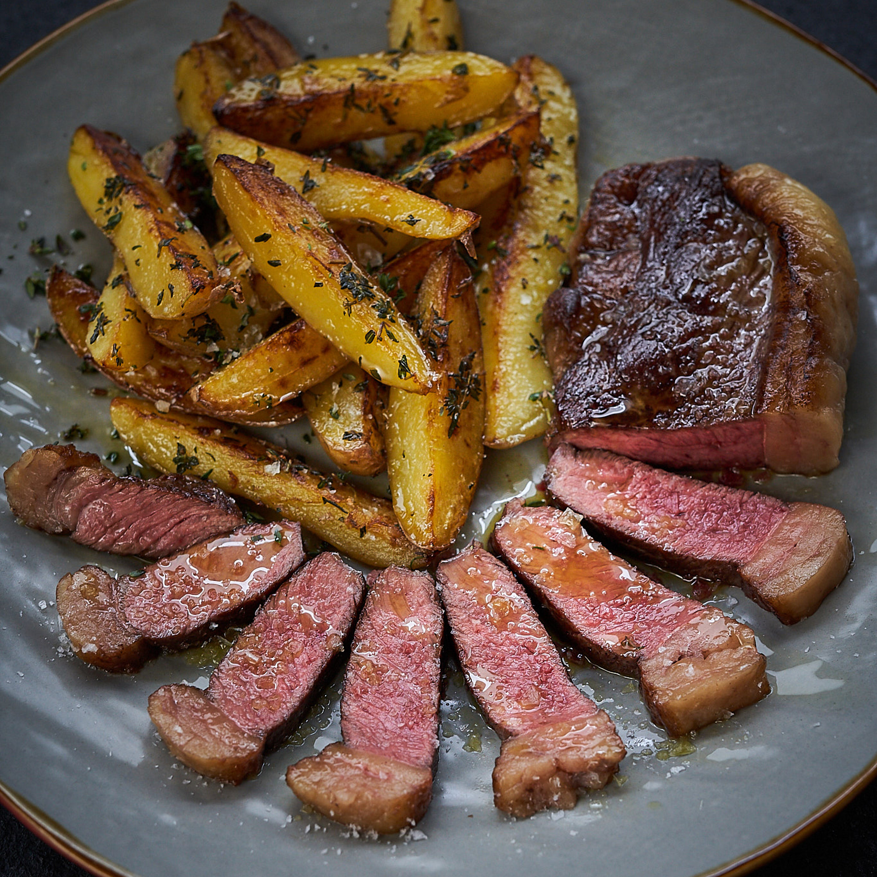 Dry-Aged Rumpsteak mit rosa Kern serviert mit Steak-Fries