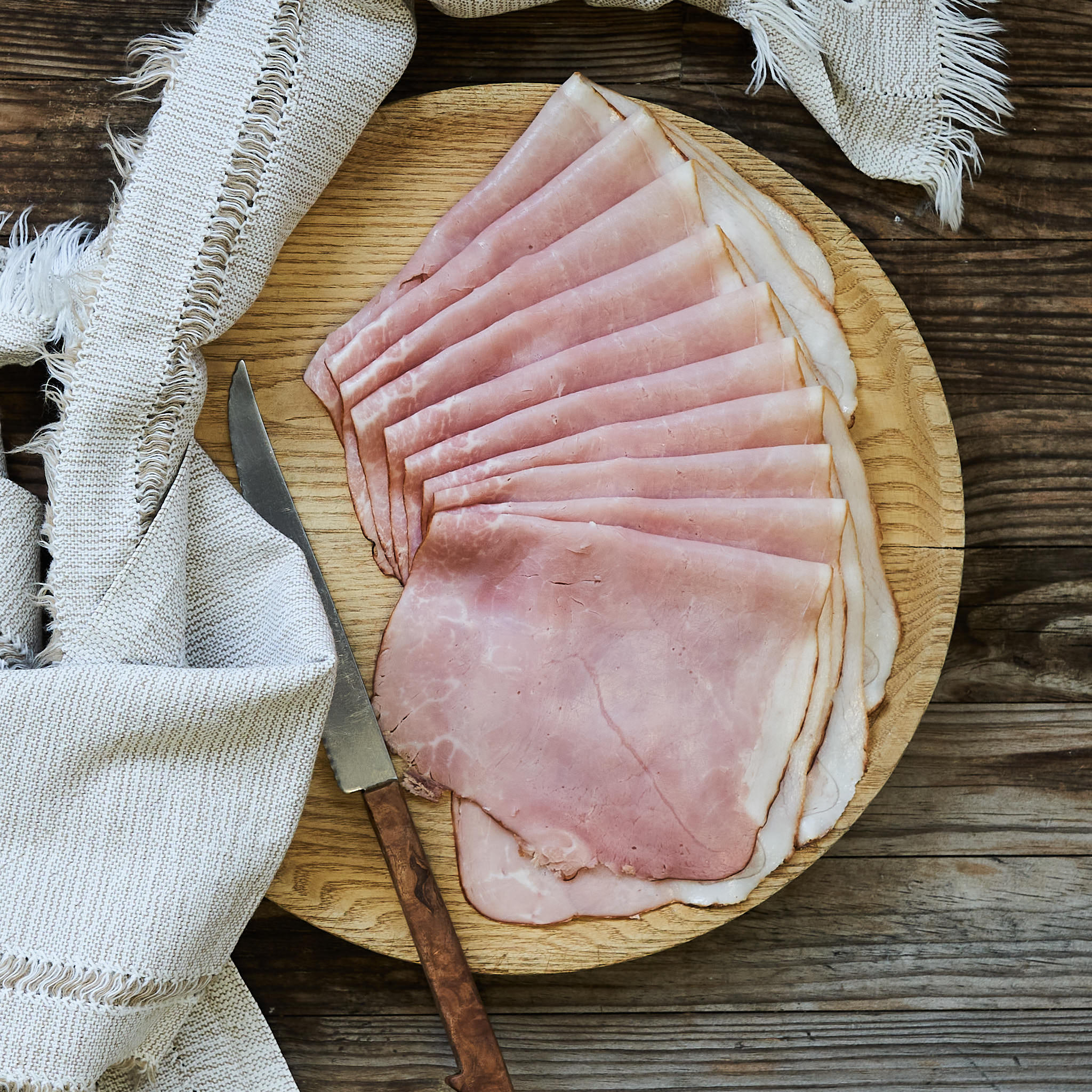 Honigkrustenschinken angerichtet auf rundem Holzbrett