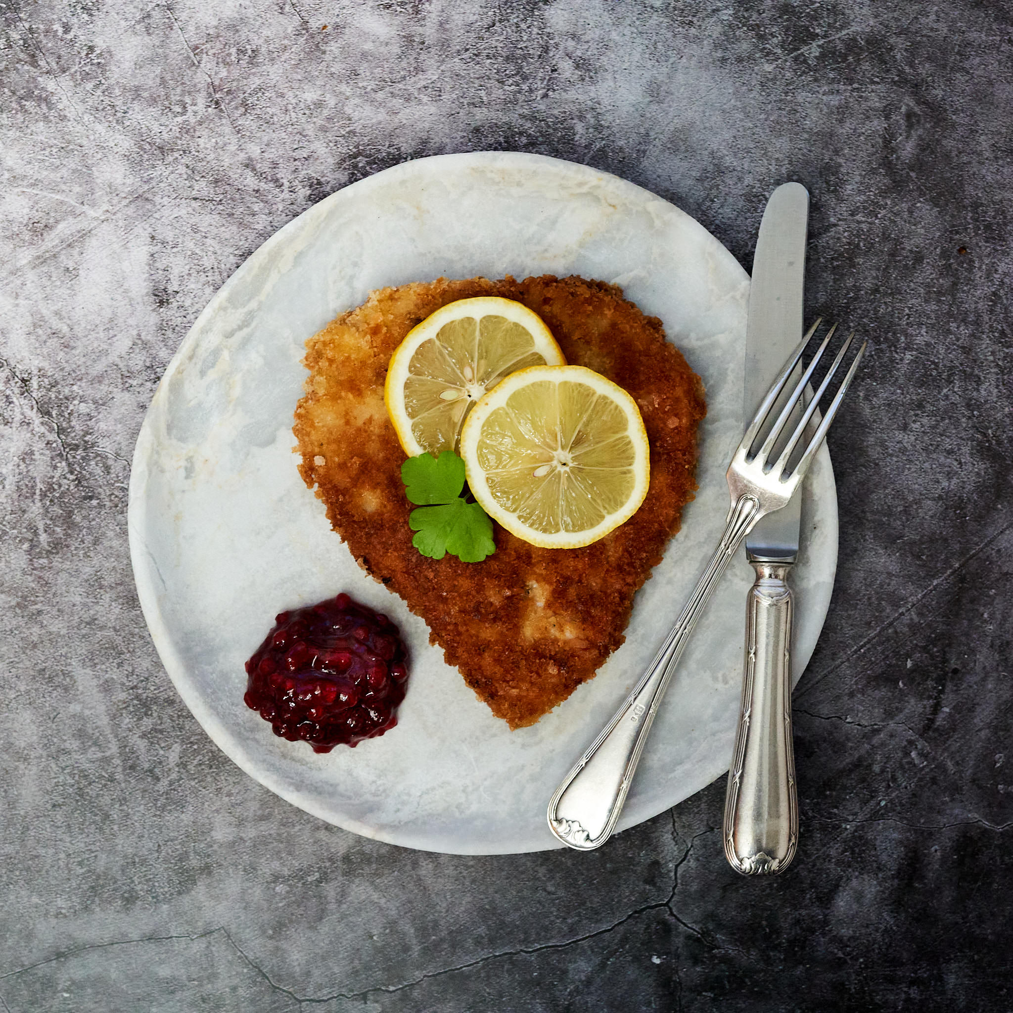 Kaiserschnitzel von der Schale paniert und in Herzform mit zwei Zitronenscheiben serviert